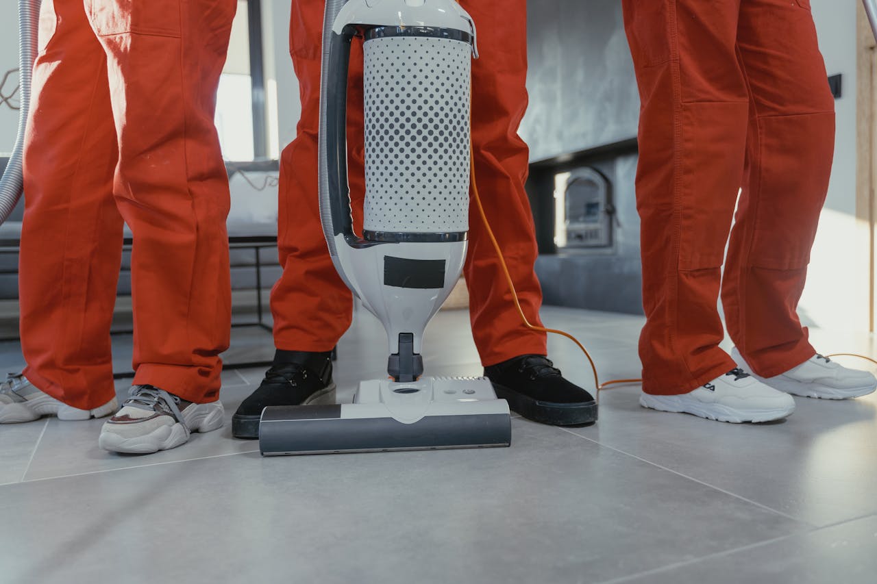 gallery-6 Team of professional cleaners in red uniforms using a vacuum cleaner indoors.